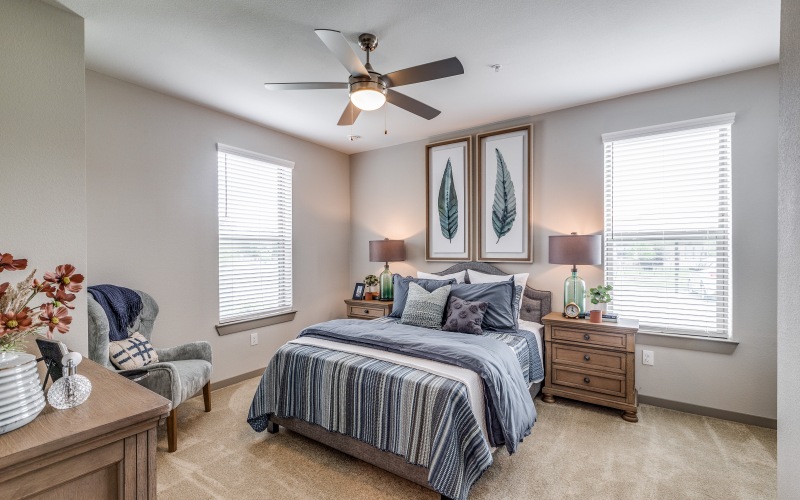 A bedroom with a queen size bed, night stands, and natural lighting